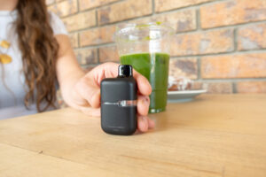 A lady holding a cannabis concentrate next to a green drink