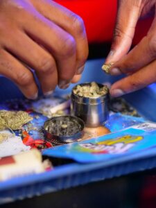 Detailed shot of hands preparing cannabis with a grinder on a colorful tray.