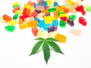 Edibles Guide: Vibrant gummy bears scattered alongside a cannabis leaf.