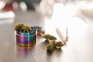 Blue Dream Strain Cannabis buds with a colorful grinder on a table.