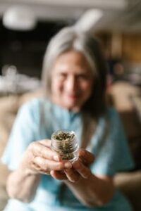 A senior woman holding a glass jar containing cannabis, representing legal marijuana use.