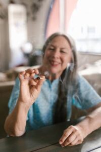 A senior woman enjoying a cannabis joint indoors with a blurred background.